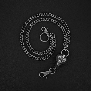 Gros plan du pendentif tête de mort punk sur une chaîne épaisse sur fond de cuir noir