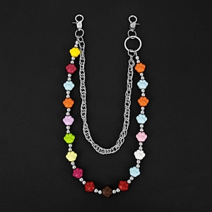 Detail showing dual-layer metal pants chain with colorful resin cat paw beads on leather