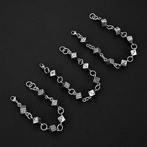 Dettaglio macro di ciondoli a dado in argento su bracciali punk in acciaio inossidabile