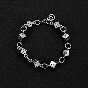 Dettaglio di un bracciale con dadi argentati su pelle nera, catena punk con moschettone