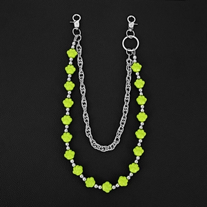 Close-up of double-layer metal pant chain with green paw beads on black leather background