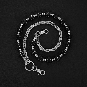 Detail of silver metal hip-hop waist chain with black dice beads on leather background
