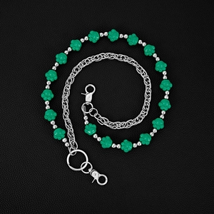 Detail of green cat paw beads and silver metal chain on black lychee leather