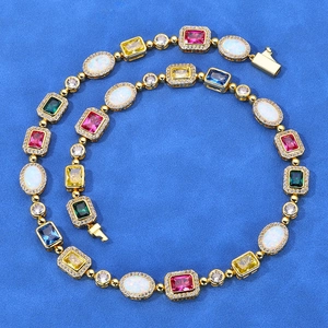 Gros plan du collier de tennis avec pierres précieuses colorées et cristaux sur tissu bleu