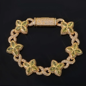 Macro detail of gold Cuban bracelet with green gems and diamond micro-pave setting