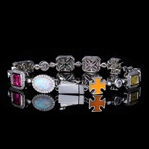 Detailopname van kleurrijke edelstenen en oranje kruis op een zilveren schakelarmband