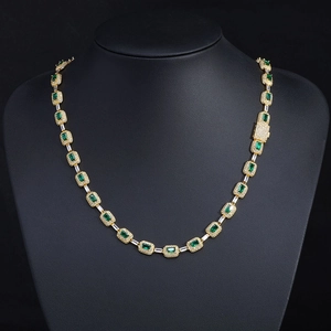 Macro detail of emerald-cut green gemstones with zircon pavé setting on a gold necklace