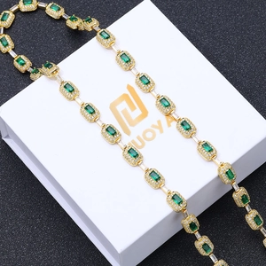 Close-up of gold chain featuring rectangle-cut green gemstones and micro-pave zircons
