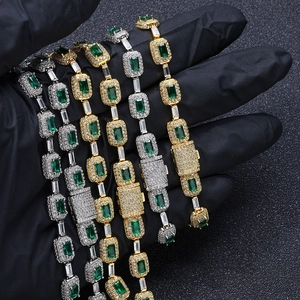 Detailed close-up of gold and silver bracelets featuring emerald-cut green zircon stones