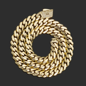 Detail of 14K gold Cuban link chain with a diamond-encrusted S-logo clasp on black surface