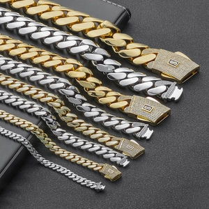 Detail of 14K gold and silver Cuban chains with iced-out S logo clasp in various widths