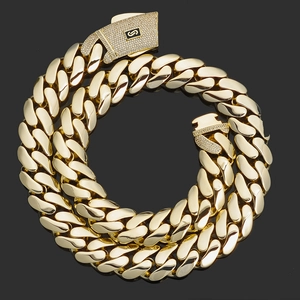 Macro detail of 14K gold Cuban chain with iced out S-logo buckle on black background