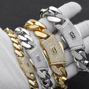 Detailed close-up of 14K gold and silver Cuban link bracelets with iced-out S buckle