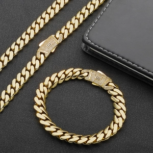 Vue macro de l'ensemble chaîne cubaine en or 14 carats avec boucle logo S micro-pavée sur noir