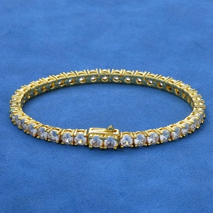 Dettaglio del bracciale tennis dorato con zirconi incastonati su sfondo di velluto blu