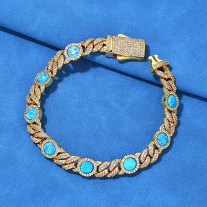 Détail d'un bracelet gourmette dorée avec des opales bleues et des cristaux pavés
