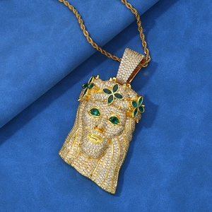 Macro detail of iced out gold Jesus pendant with green stones and sparkling zircons
