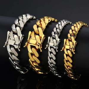 Polished gold and silver Cuban link bracelets displayed on a black cylindrical stand