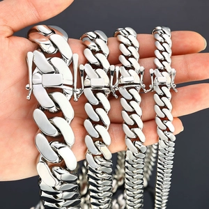 Close-up of four silver Cuban link chains in different widths held in hand for comparison