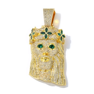 Macro detail of gold-plated Jesus head hip hop pendant with cubic zirconia and green stones