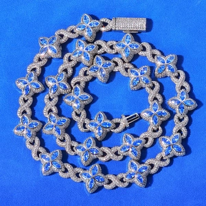 Macro detail of silver Cuban chain featuring blue moissanite clover and iced-out links