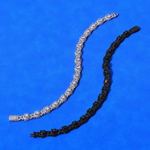 Detail of silver and black iced out 7.5mm cuban link bracelets on blue background