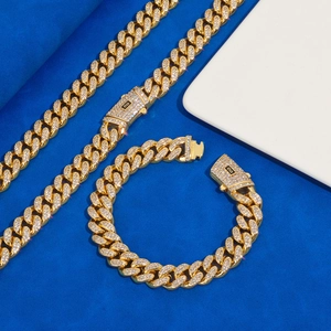 Dettaglio del set catena cubana dorata con pavé di zirconi su sfondo blu scuro