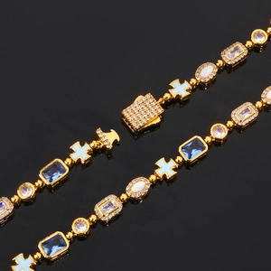 Bracelet croix doré avec cristaux bleus et opale blanche sur surface noire réfléchissante