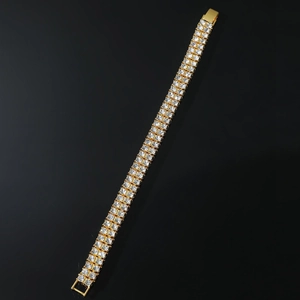 Macro detail of gold-plated double-row tennis bracelet with crystal pave on black background