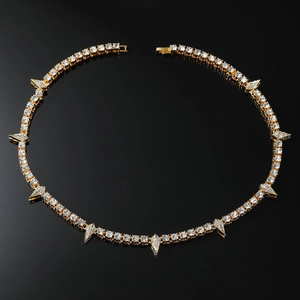 Macro detail of gold tennis chain with iced-out spike charms and cubic zirconia stones