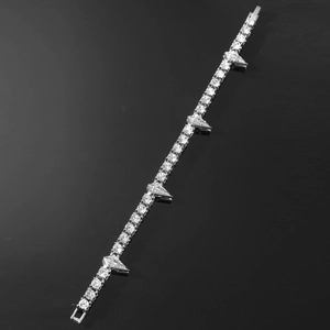 Détail macro du bracelet tennis hip hop argenté avec strass et breloques pointes punk