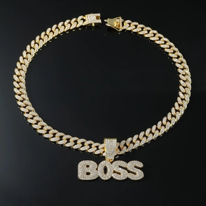 Gros plan du pendentif BOSS doré avec cristaux pavés sur une chaîne cubaine hip-hop