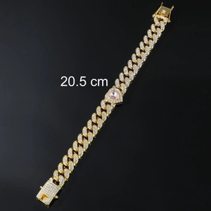Detail of gold Cuban chain bracelet featuring pink heart gem and white sparkling diamonds