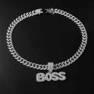 Détail macro du pendentif BOSS serti et chaîne cubaine sur fond noir brillant de luxe