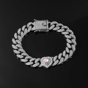 Macro view of iced out silver Cuban link bracelet with large pink heart-shaped stone