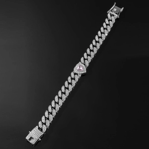 Macro shot of silver Cuban link chain featuring a pink heart stone and iced out cubic zirconia