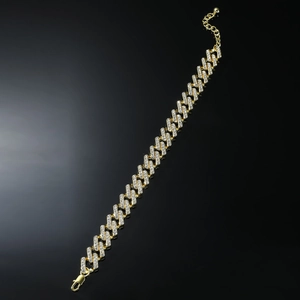Détail de la chevillère gourmette dorée sertie de strass brillants avec fermoir mousqueton