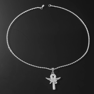Macro shot of silver Ankh cross pendant with wings and rope chain on a black mirror