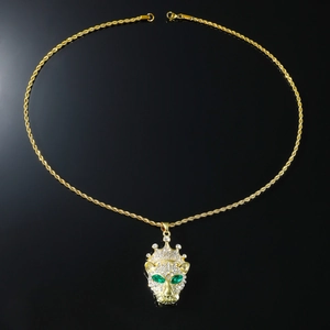 Detailed close-up of a gold-plated leopard pendant with green eyes and crystal crown
