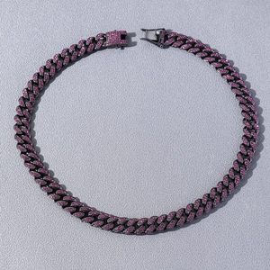 Macro view of iced out Cuban link chain featuring pink rhinestones on black metal