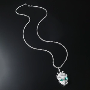 Macro shot of silver hip-hop leopard pendant with crown and green gemstone eyes