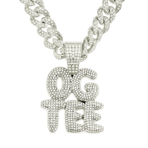 Gros plan sur un collier Cuban hip-hop argenté avec pendentif OG TEE serti de strass