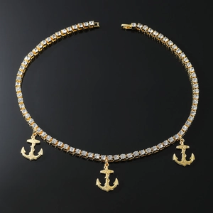 Détail d'une chaîne tennis dorée avec trois pendentifs ancre sertis de faux diamants