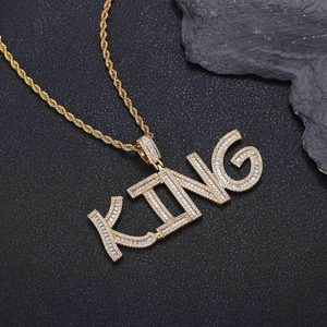 Macro shot of gold hip hop KING pendant with pave cubic zirconia on black texture