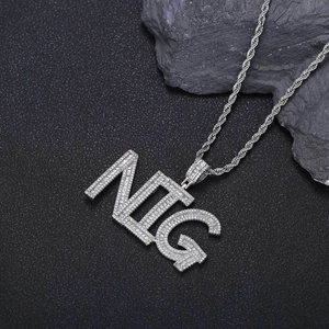 Close-up of iced out NTG letter pendant with cubic zirconia on black matte surface