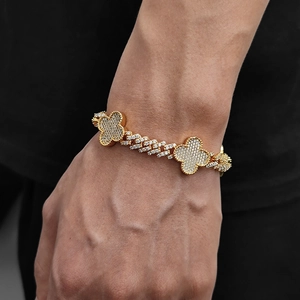 Dettaglio macro del bracciale cubano dorato da uomo con maglie a quadrifoglio e zirconi