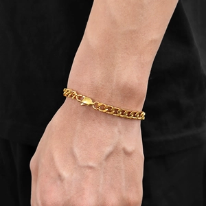 Macro view of polished 6mm gold Cuban chain bracelet with lobster clasp on male wrist