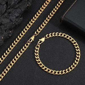 Macro detail of gold Cuban link chain set with necklace and bracelet on dark stone texture