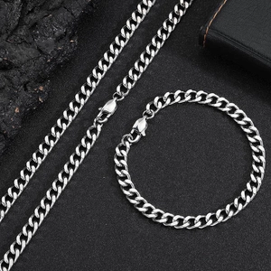 Detailed top view of polished 6mm silver Cuban link necklace and bracelet set on black stone