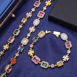Dettaglio di un set di gioielli d'oro con gemme colorate e croci su tessuto blu